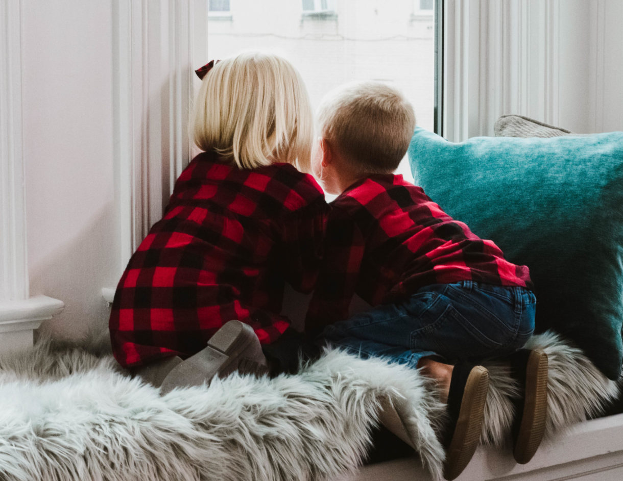 two children looking out a window